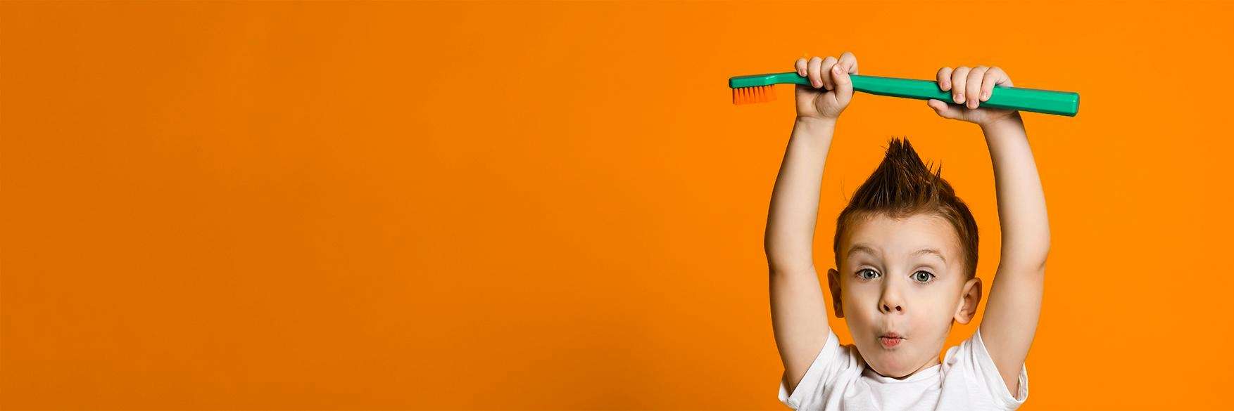 A happy child holding a toothbrush after dental check up at Edmond Dental Center